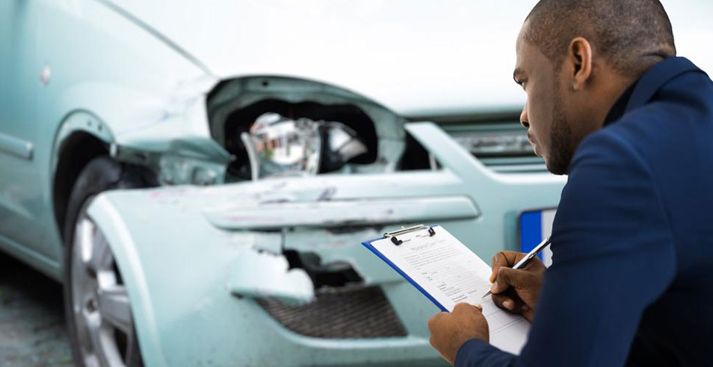 Deux personnes debout près d'un véhicule de collection, l'une tenant une tablette, l'autre montrant un détail sur la carrosserie, vues de profil en lumière naturelle extérieure Deux personnes debout près d'un véhicule de collection, l'une tenant une tablette, l'autre montrant un détail sur la carrosserie, vues de profil en lumière naturelle extérieure